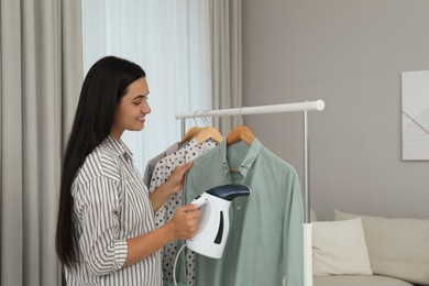 Woman steaming shirt on hanger at home Photo of Woman steaming shirt on hanger at home