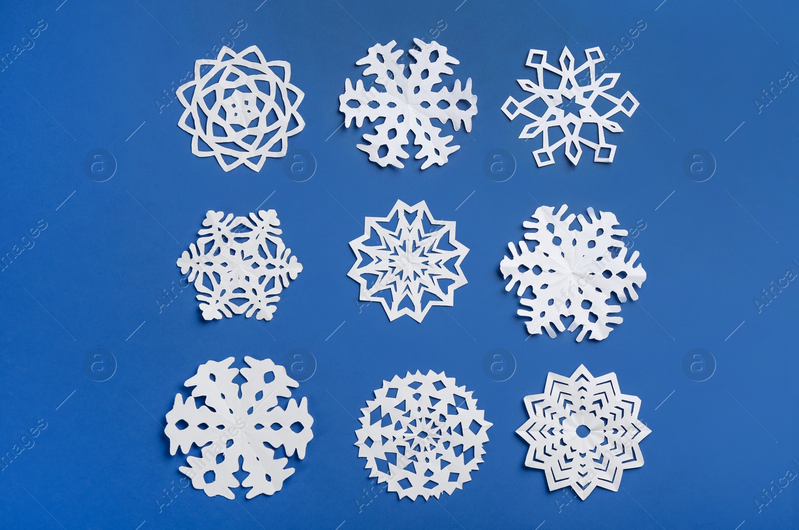 Many paper snowflakes on blue background, flat lay Photo of Many paper snowflakes on blue background, flat lay