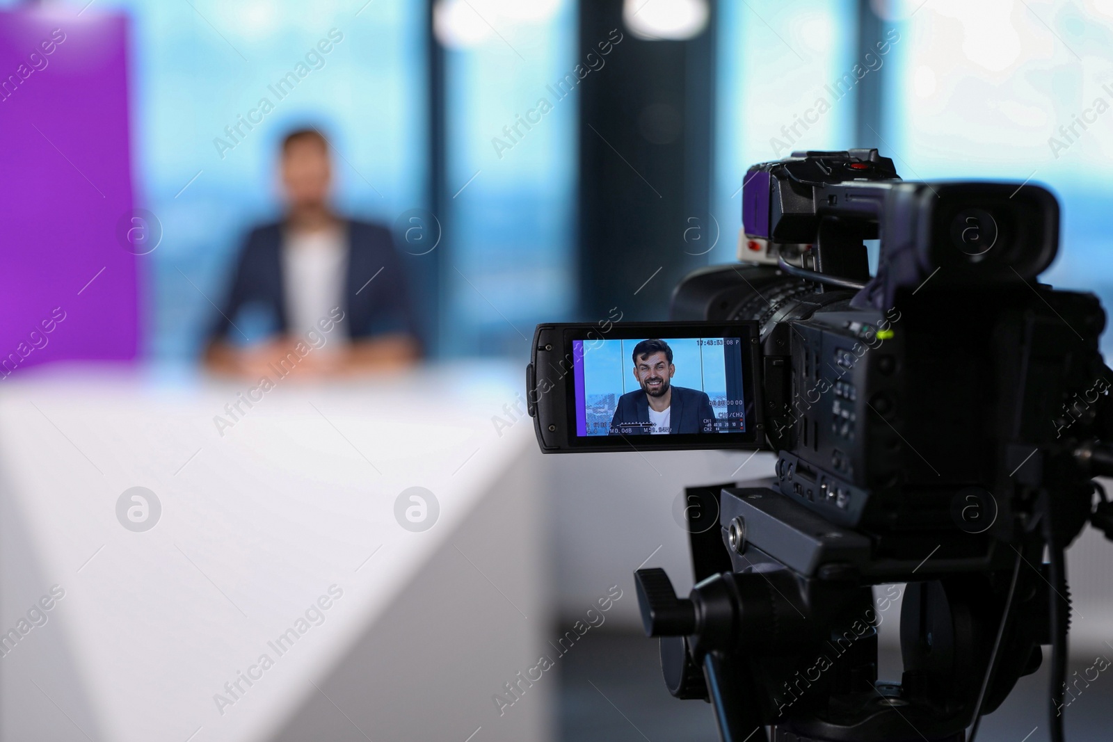 Photo of Presenter working in studio, focus on video camera