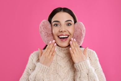 Beautiful young woman wearing earmuffs on pink background Photo of Beautiful young woman wearing earmuffs on pink background