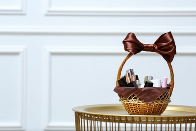 Gift set in wicker basket on golden table near white wall. Space for text Photo of Gift set in wicker basket on golden table near white wall. Space for text
