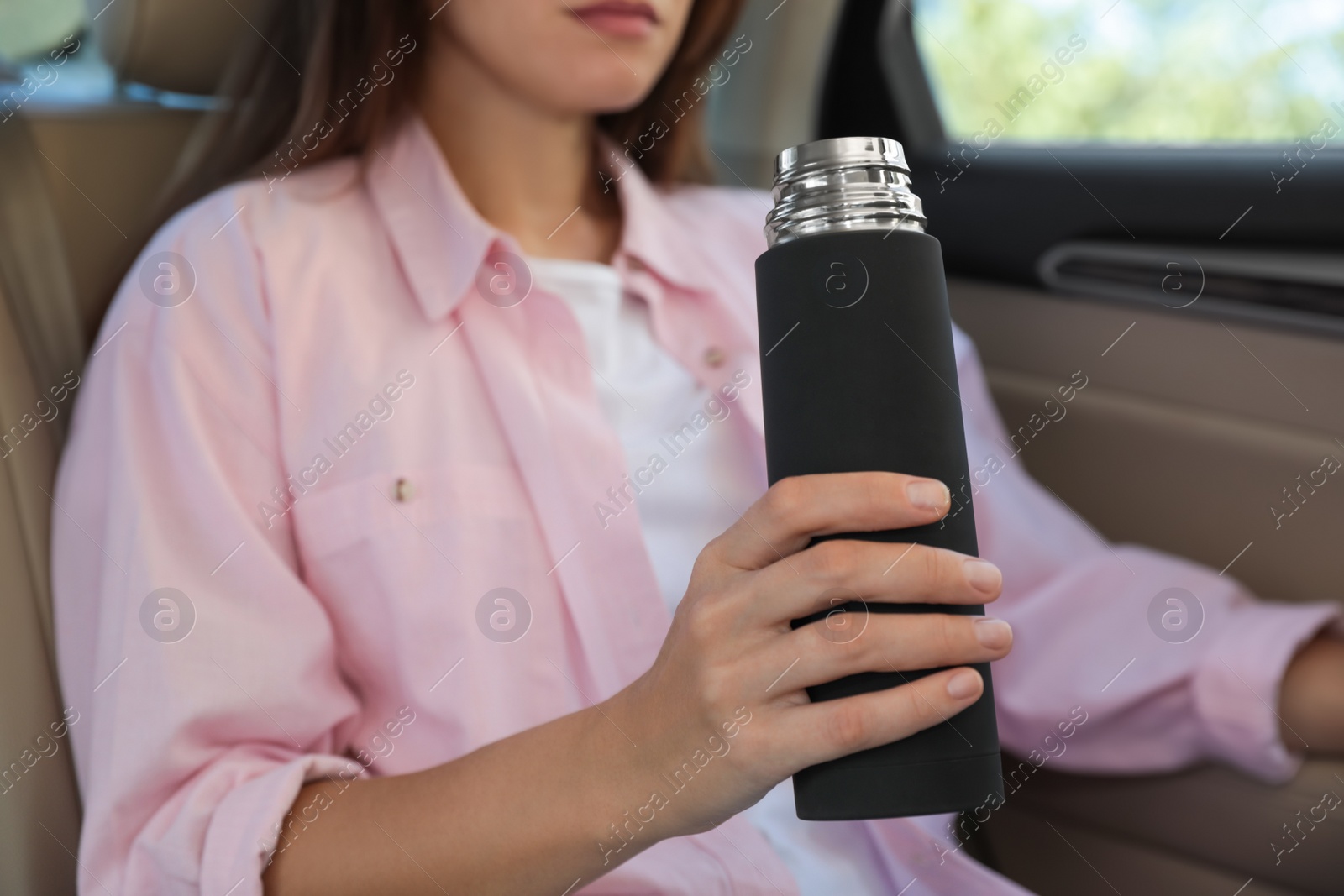 Woman with thermos inside of car, closeup Photo of Woman with thermos inside of car, closeup