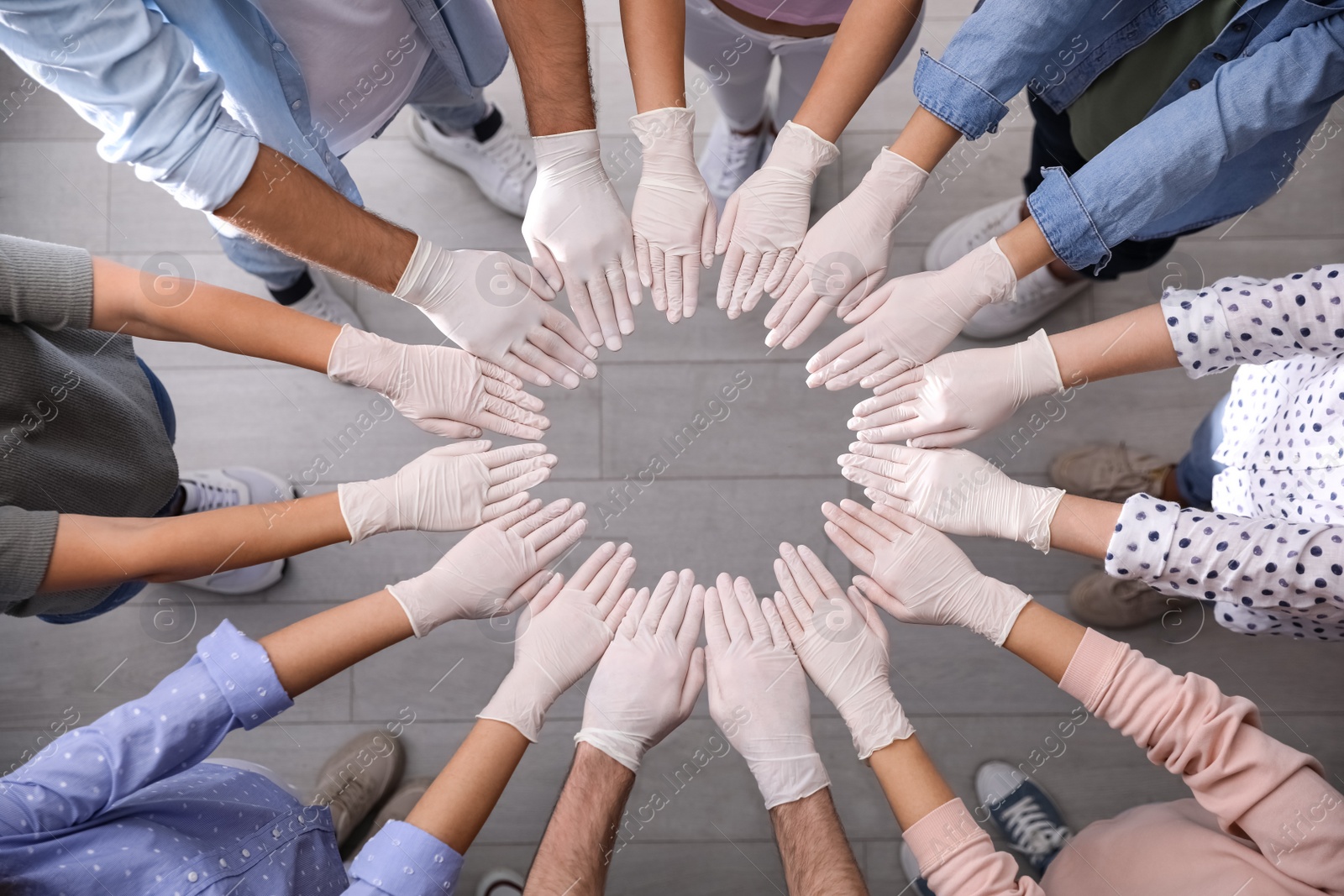 People in white medical gloves joining hands indoors, top view Photo of People in white medical gloves joining hands indoors, top view