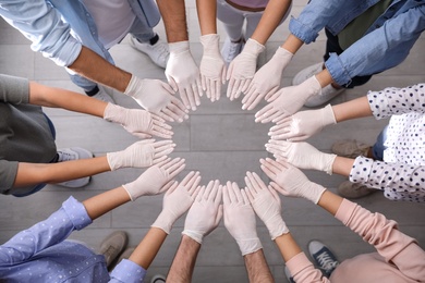 People in white medical gloves joining hands indoors, top view Photo of People in white medical gloves joining hands indoors, top view
