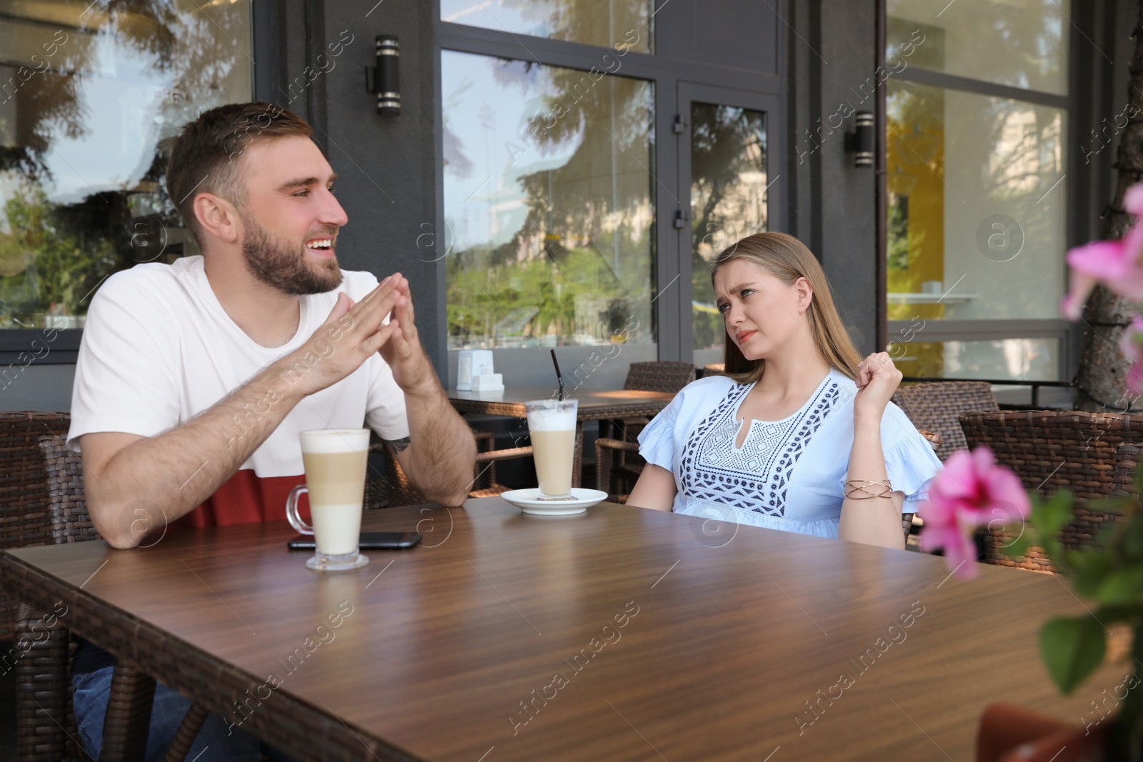 Young woman having boring date with guy in outdoor cafe Photo of Young woman having boring date with guy in outdoor cafe