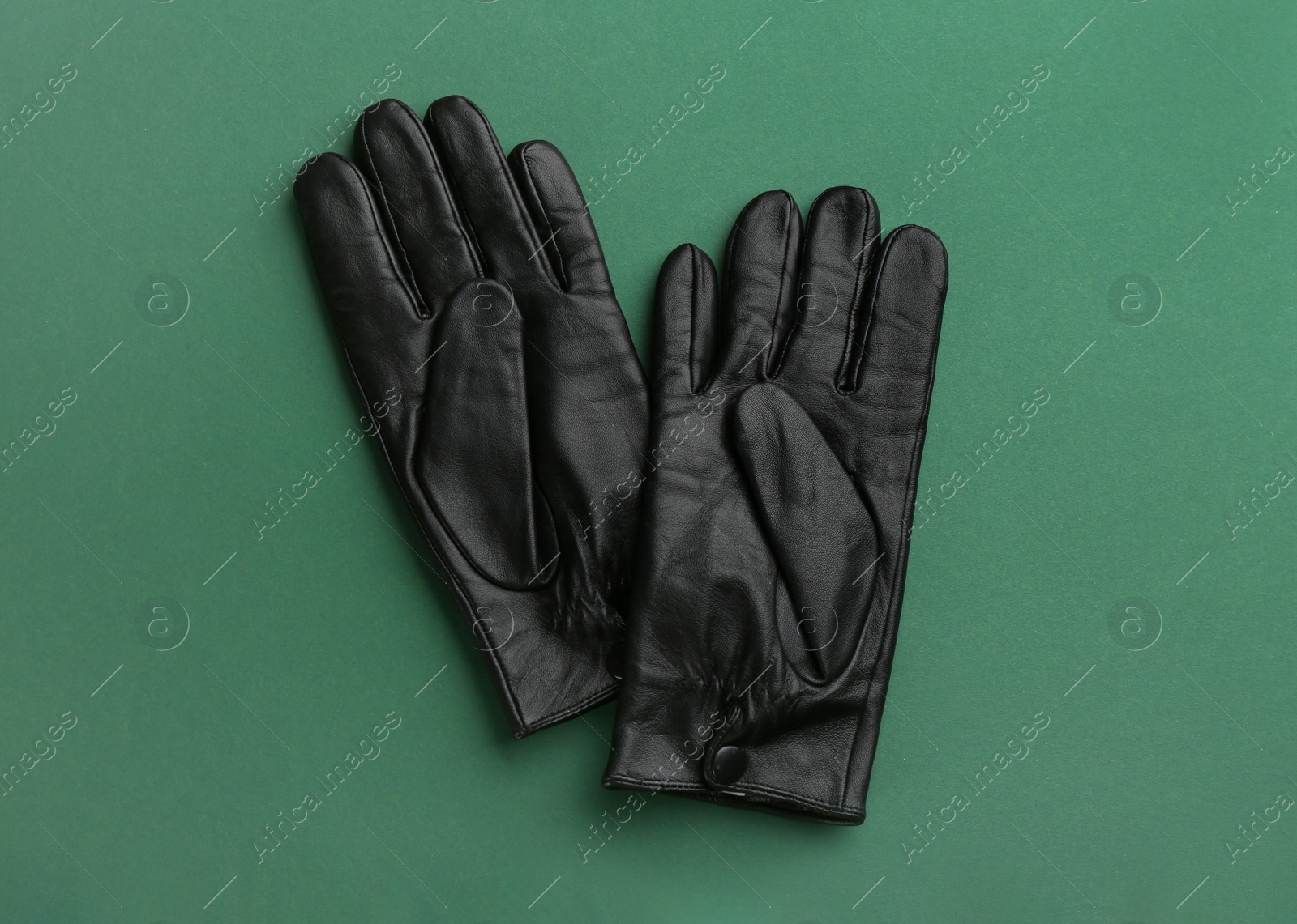 Pair of stylish leather gloves on green background, flat lay Photo of Pair of stylish leather gloves on green background, flat lay