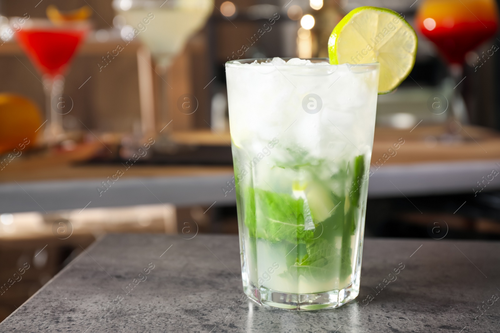 Photo of Mojito cocktail on grey table in bar. Space for text