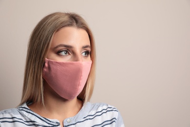 Young woman in protective face mask on beige background. Space for text Photo of Young woman in protective face mask on beige background. Space for text