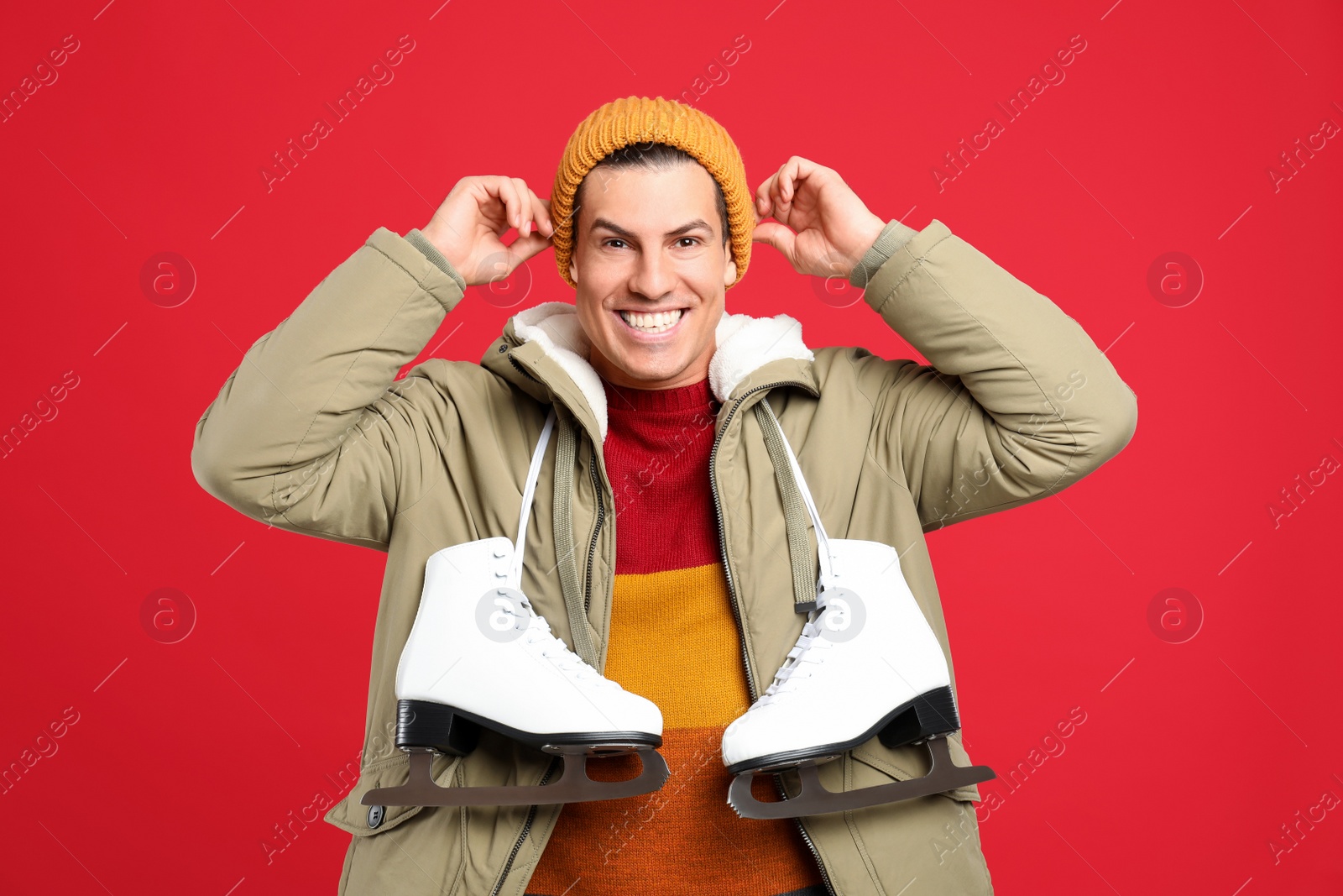 Photo of Emotional man with ice skates on red background