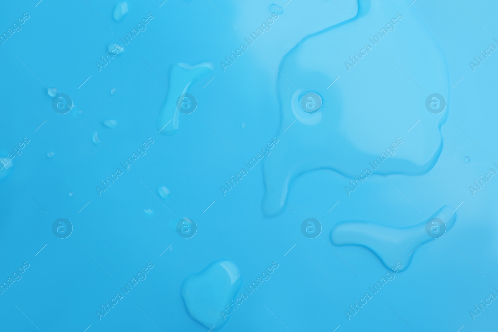 Drops of spilled water on light blue background, top view Photo of Drops of spilled water on light blue background, top view