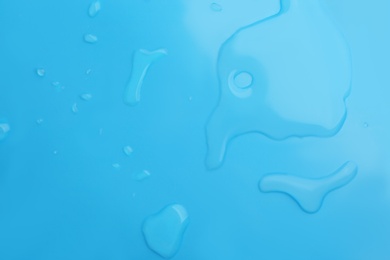 Drops of spilled water on light blue background, top view Photo of Drops of spilled water on light blue background, top view