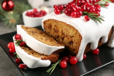 Traditional classic Christmas cake decorated with cranberries, pomegranate seeds and rosemary on black plate, closeup Photo of Traditional classic Christmas cake decorated with cranberries, pomegranate seeds and rosemary on black plate, closeup