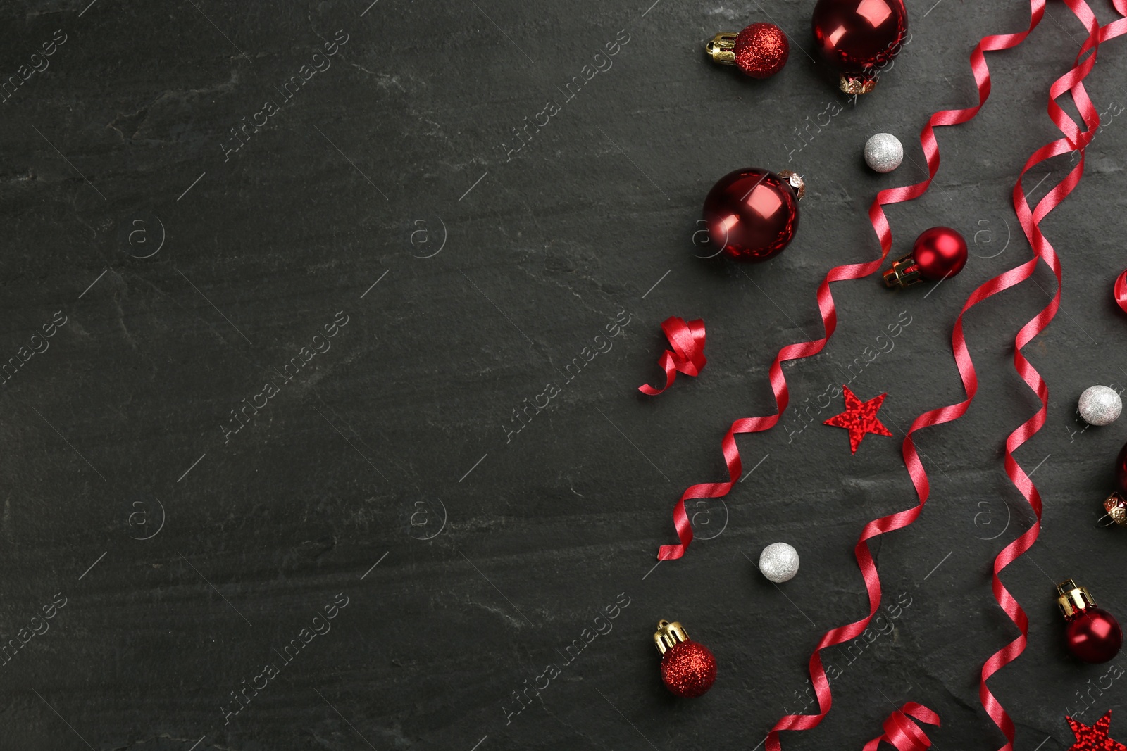 Shiny serpentine streamers and Christmas balls on black background, flat lay. Space for text Photo of Shiny serpentine streamers and Christmas balls on black background, flat lay. Space for text