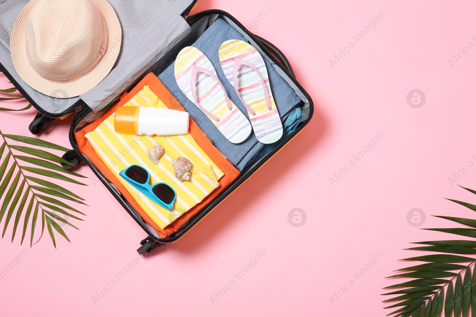 Photo of Flat lay composition with open suitcase and space for text on pink background