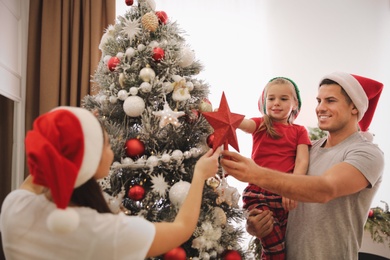 Family decorating Christmas tree with star topper indoors Photo of Family decorating Christmas tree with star topper indoors