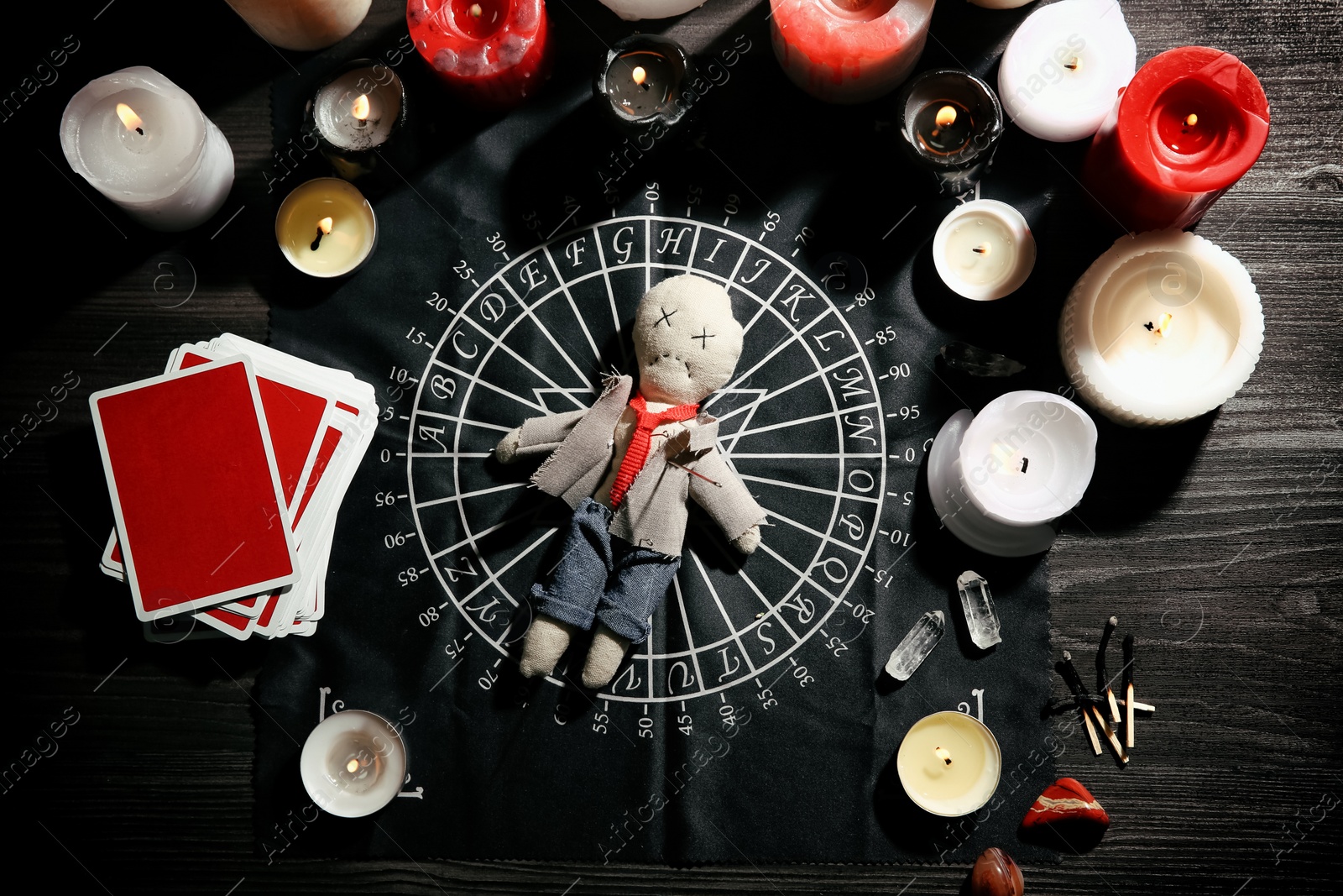 Voodoo doll pierced with needle surrounded by ceremonial items on table, flat lay Photo of Voodoo doll pierced with needle surrounded by ceremonial items on table, flat lay