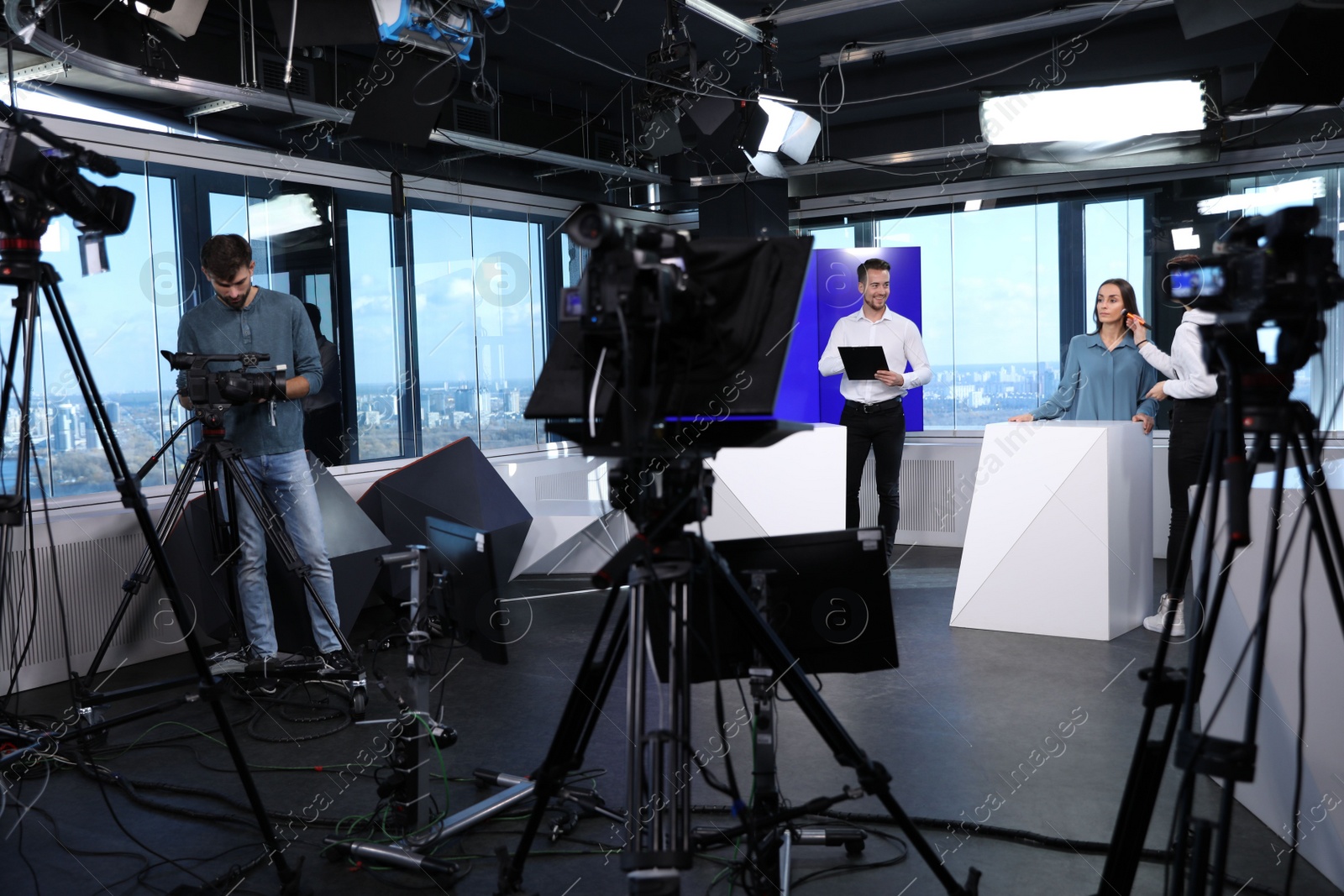 Presenters, makeup artist and video camera operator working in studio. News broadcasting Photo of Presenters, makeup artist and video camera operator working in studio. News broadcasting