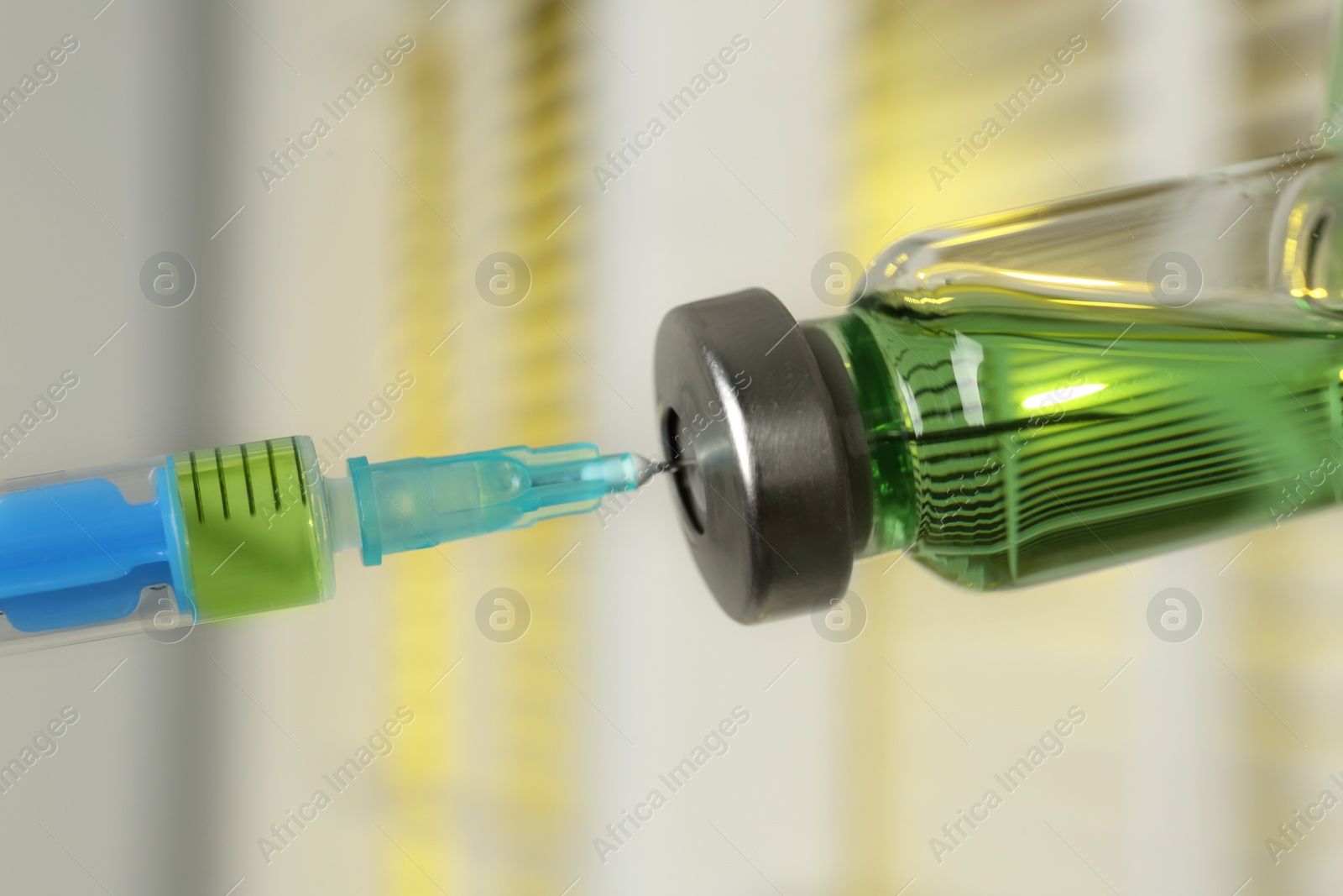 Filling syringe with medication from vial against blurred background, closeup. Vaccination and immunization Photo of Filling syringe with medication from vial against blurred background, closeup. Vaccination and immunization