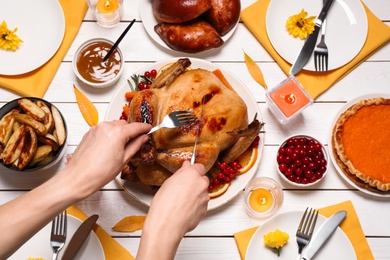 Woman eating traditional cooked turkey at white wooden table, top view. Thanksgiving day celebration Photo of Woman eating traditional cooked turkey at white wooden table, top view. Thanksgiving day celebration