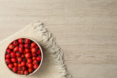 Ripe rose hip berries in bowl on wooden table, top view. Space for text Photo of Ripe rose hip berries in bowl on wooden table, top view. Space for text