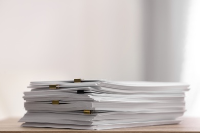 Stack of blank paper with binder clips on wooden table. Space for text Photo of Stack of blank paper with binder clips on wooden table. Space for text