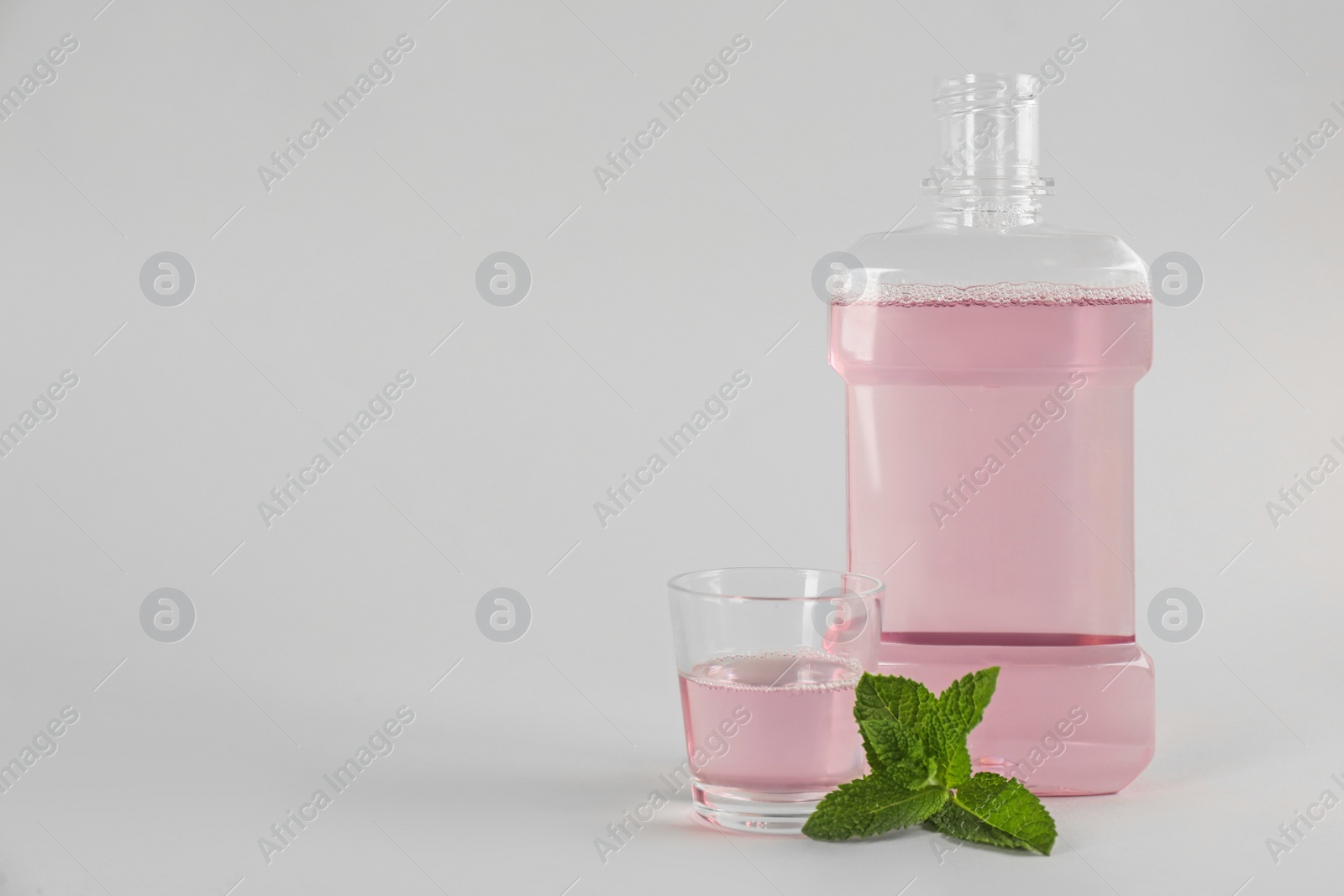 Mouthwash and fresh mint on light grey background. Space for text Photo of Mouthwash and fresh mint on light grey background. Space for text