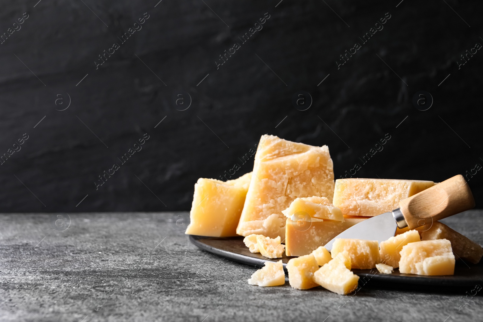 Parmesan cheese with board and knife on grey table. Space for text Photo of Parmesan cheese with board and knife on grey table. Space for text
