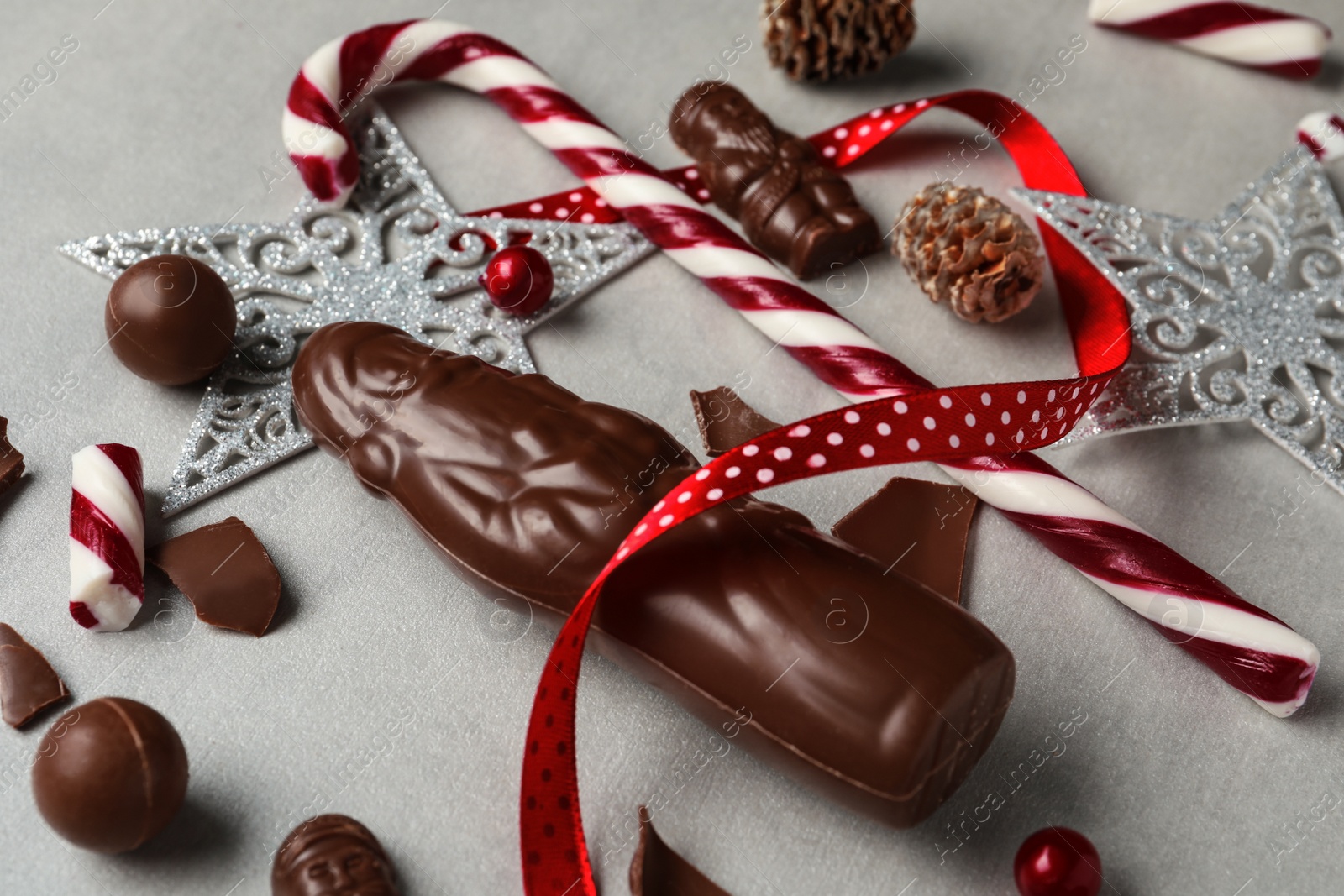 Photo of Composition with chocolate Santa Claus candies and Christmas decorations on light grey table
