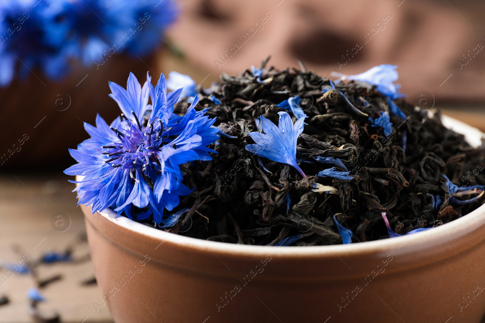 Bowl with dry tea leaves and cornflower, closeup Photo of Bowl with dry tea leaves and cornflower, closeup