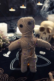 Voodoo doll with pins and dried flowers on table indoors Photo of Voodoo doll with pins and dried flowers on table indoors