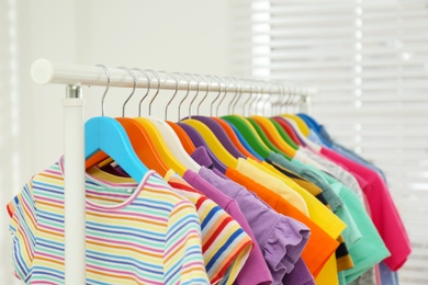 Photo of Different child's clothes hanging on rack in room