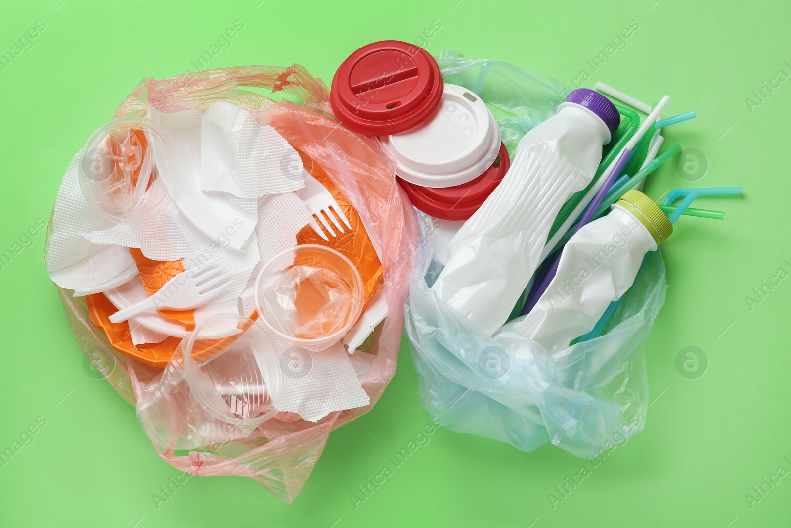 Pile of different plastic items on green background, flat lay Photo of Pile of different plastic items on green background, flat lay