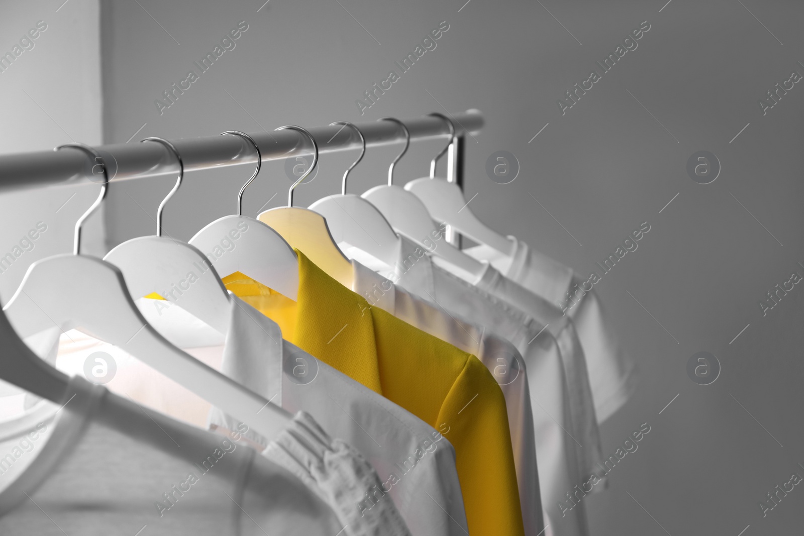 Yellow jacket hanging on rack among other clothes. Diversity concept Photo of Yellow jacket hanging on rack among other clothes. Diversity concept