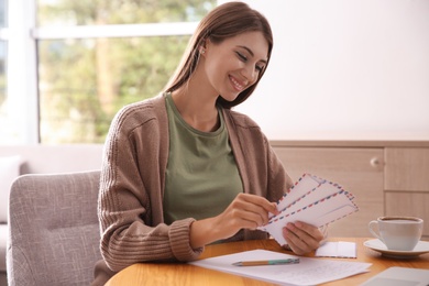 Woman with letter at wooden table in room Photo of Woman with letter at wooden table in room