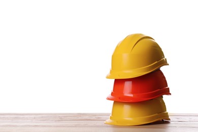 Different hard hats on wooden table against white background. Space for text Photo of Different hard hats on wooden table against white background. Space for text