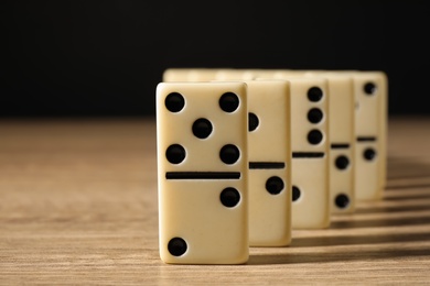 Domino tiles on wooden table against black background, closeup Photo of Domino tiles on wooden table against black background, closeup