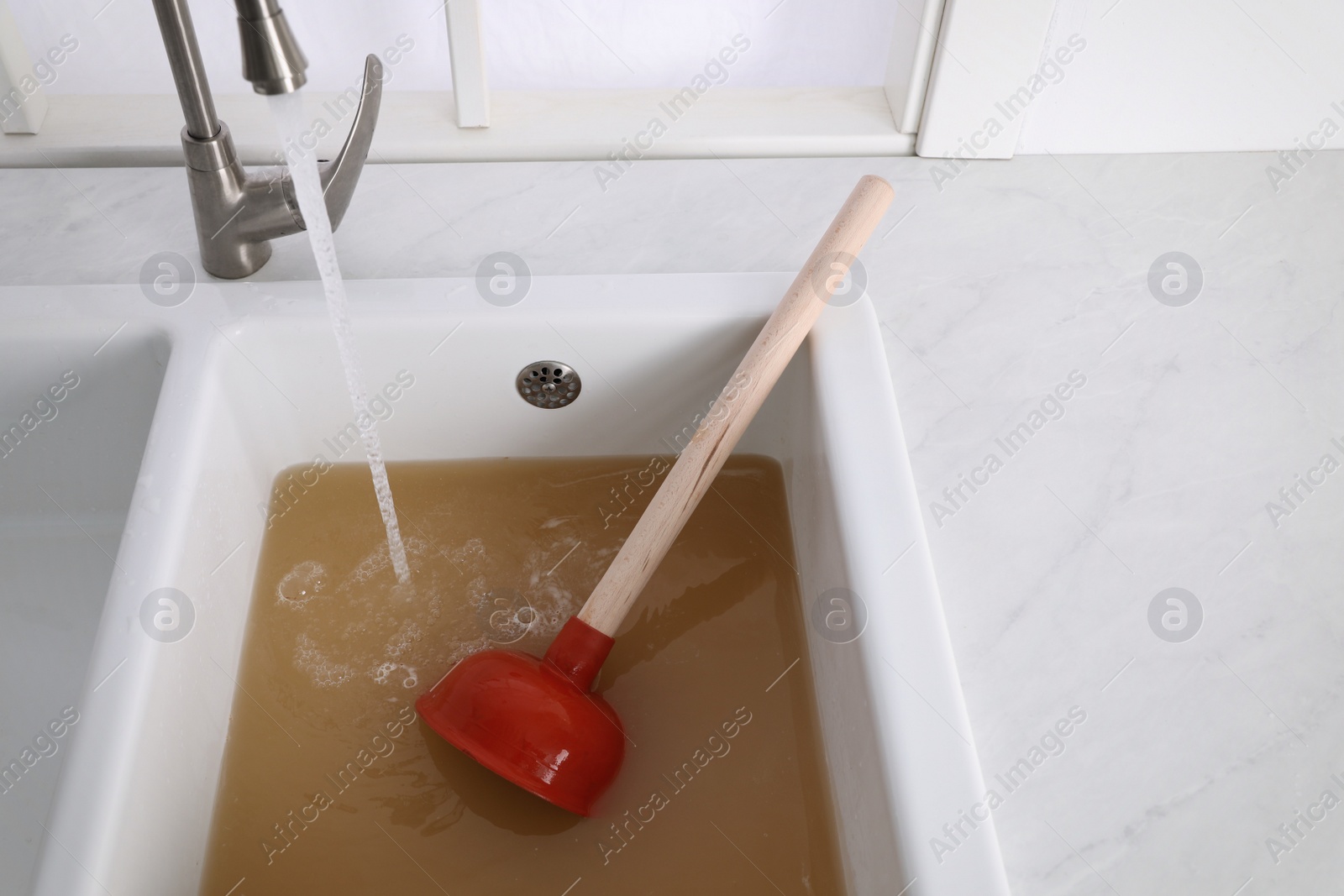 Clogged kitchen sink with plunger and dirty water Photo of Clogged kitchen sink with plunger and dirty water