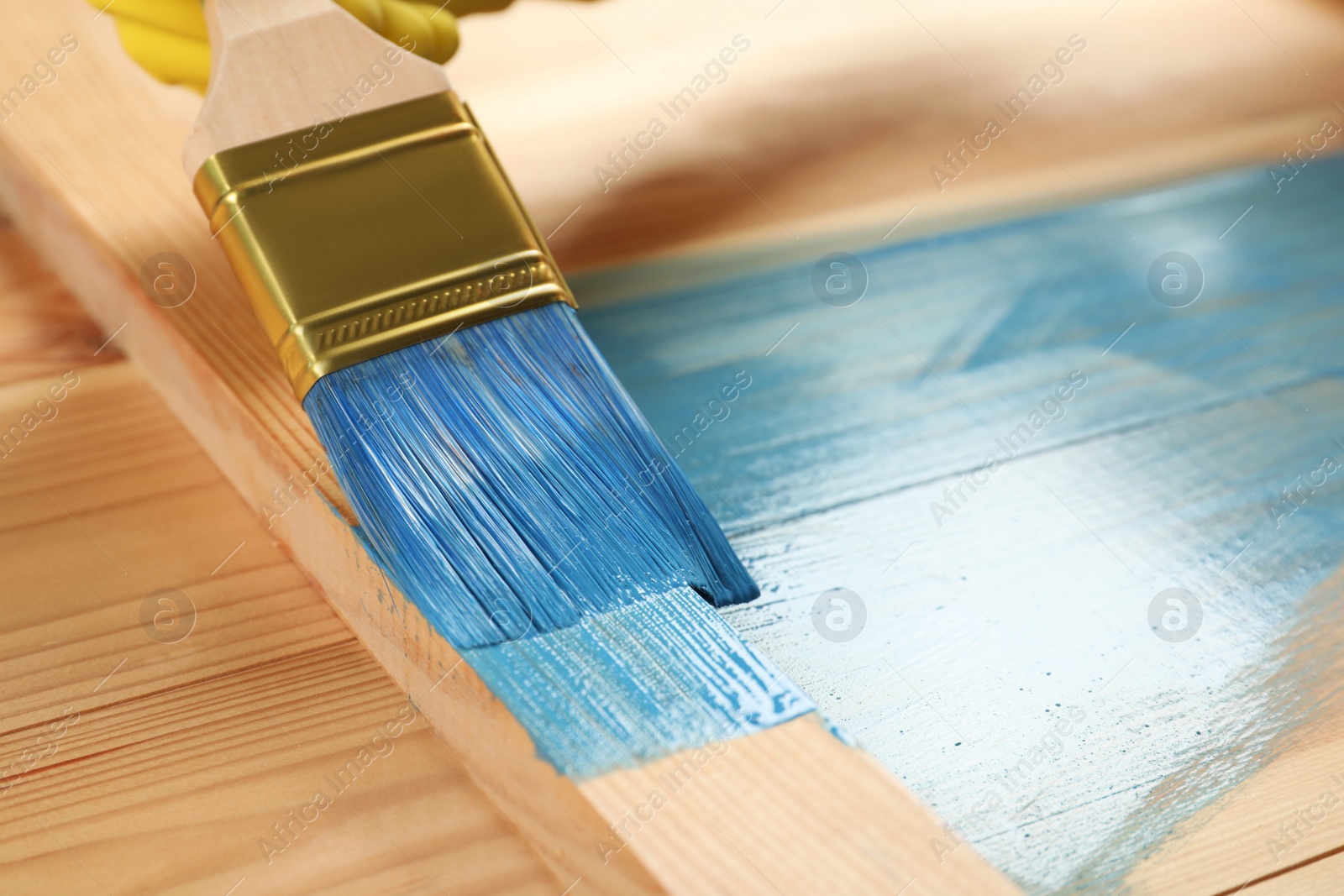Worker applying blue paint onto wooden surface, closeup. Space for text Photo of Worker applying blue paint onto wooden surface, closeup. Space for text