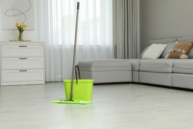 Mop and bucket on wooden floor in living room. Cleaning service Photo of Mop and bucket on wooden floor in living room. Cleaning service