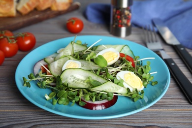 Salad with fresh organic microgreen in plate on wooden table, closeup Photo of Salad with fresh organic microgreen in plate on wooden table, closeup