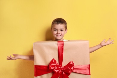 Cute little boy dressed as gift box on yellow background. Christmas suit Image of Cute little boy dressed as gift box on yellow background. Christmas suit