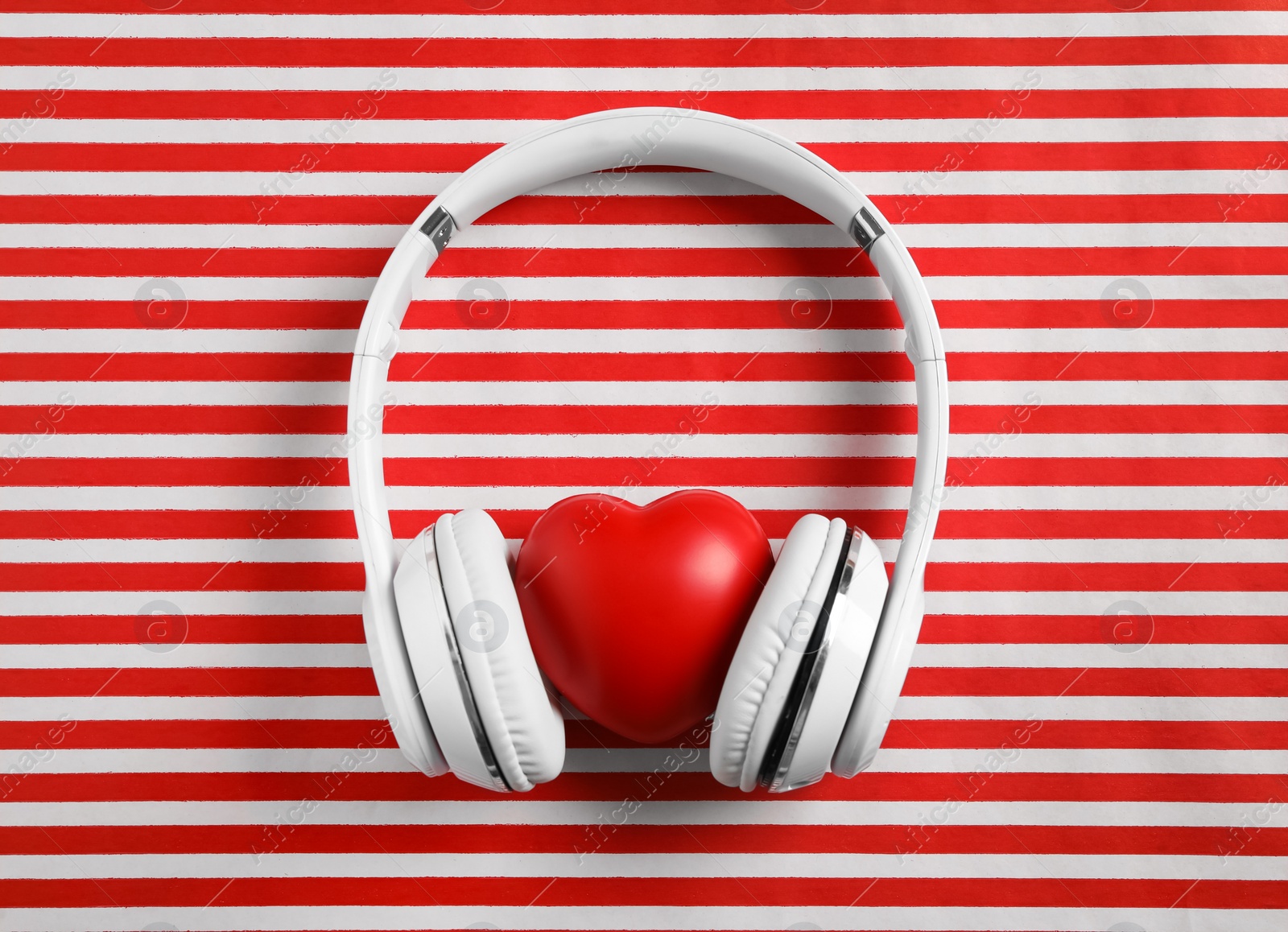 Modern headphones and red heart on color background, flat lay. Listening love music songs Photo of Modern headphones and red heart on color background, flat lay. Listening love music songs