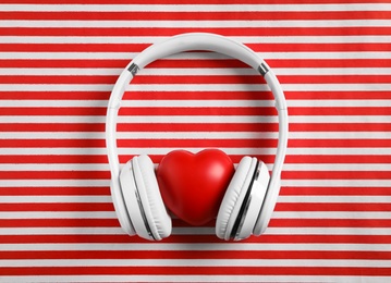 Modern headphones and red heart on color background, flat lay. Listening love music songs Photo of Modern headphones and red heart on color background, flat lay. Listening love music songs