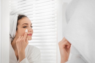 Woman using silkworm cocoon in skin care routine near mirror at home Photo of Woman using silkworm cocoon in skin care routine near mirror at home
