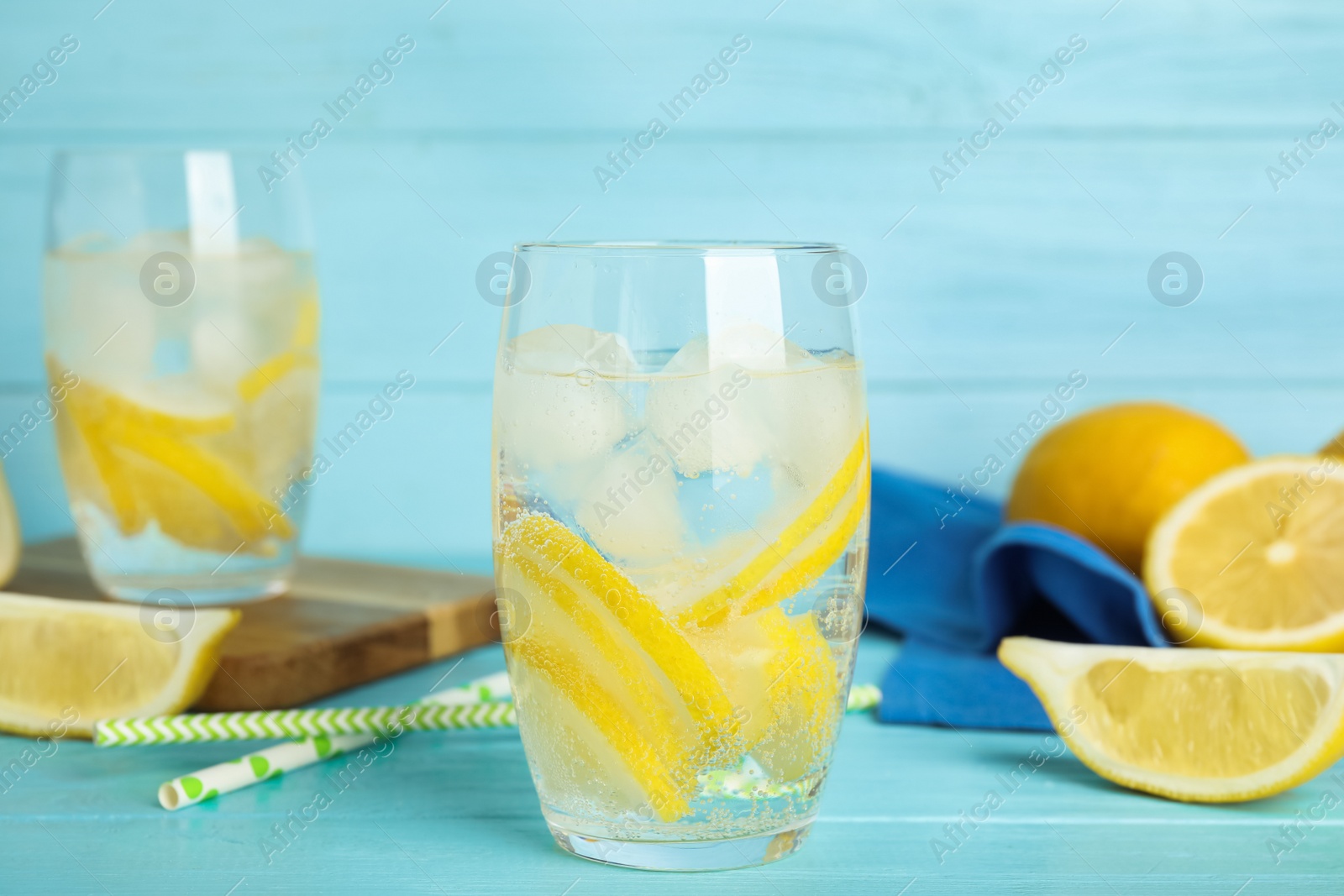 Soda water with lemon slices and ice cubes on light blue wooden table Photo of Soda water with lemon slices and ice cubes on light blue wooden table