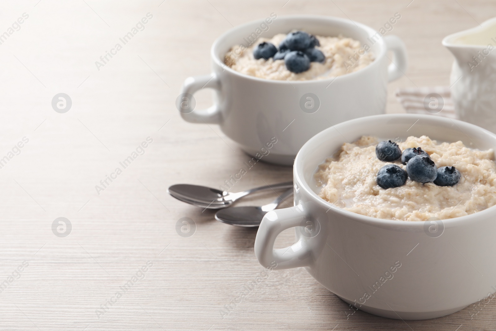 Tasty oatmeal porridge with blueberries served on light wooden table, space for text Photo of Tasty oatmeal porridge with blueberries served on light wooden table, space for text