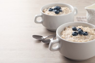 Tasty oatmeal porridge with blueberries served on light wooden table, space for text Photo of Tasty oatmeal porridge with blueberries served on light wooden table, space for text