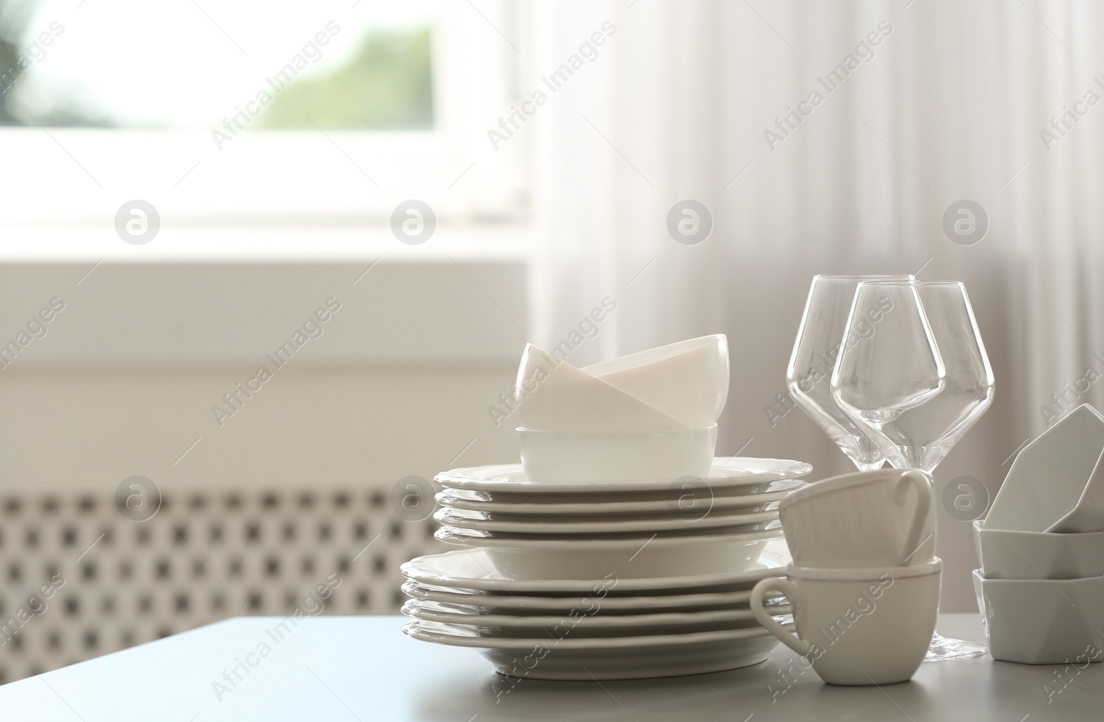Set of clean dishware and wineglasses on table indoors. Space for text Photo of Set of clean dishware and wineglasses on table indoors. Space for text
