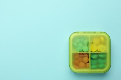Pill box with medicaments on turquoise background, top view. Space for text Photo of Pill box with medicaments on turquoise background, top view. Space for text