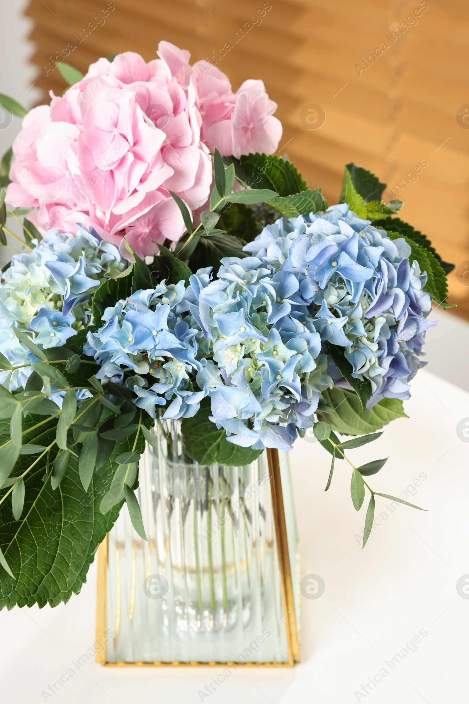Photo of Beautiful hortensia flowers in vase on white table indoors